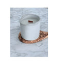 White candle in a textured holder on a marble surface